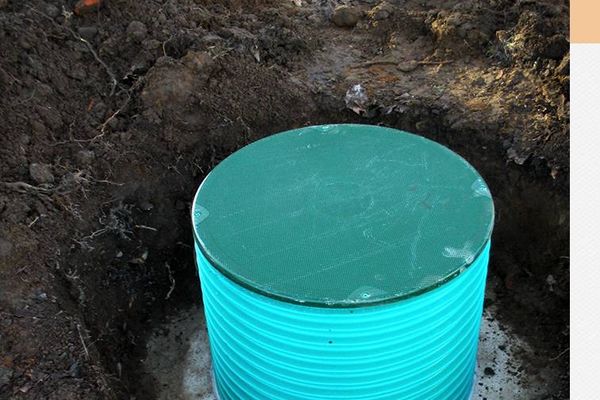Green plastic septic tank riser in excavated ground