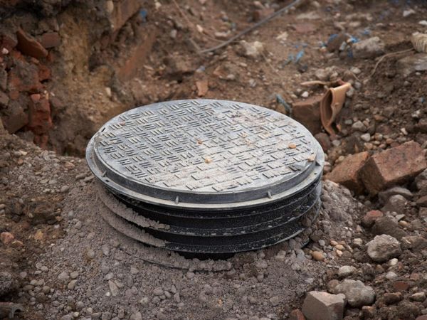 Excavated septic tank with round metal access lid